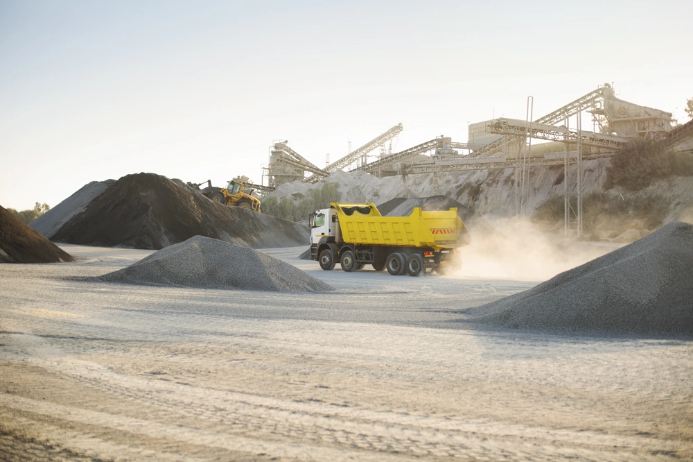 Transport kruszywa wywrotka przewożąca żwir przy hałdach i maszynach w kamieniołomie