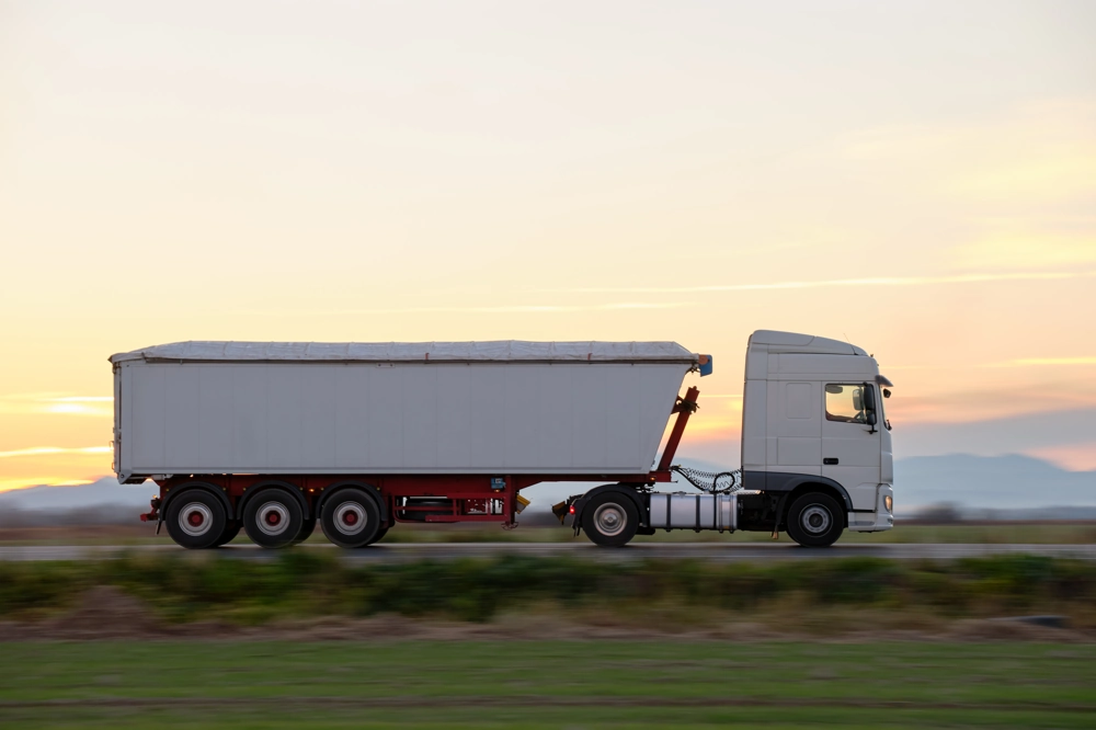 Biała ciężarówka z naczepą w długiej trasie - Usługi transportowe